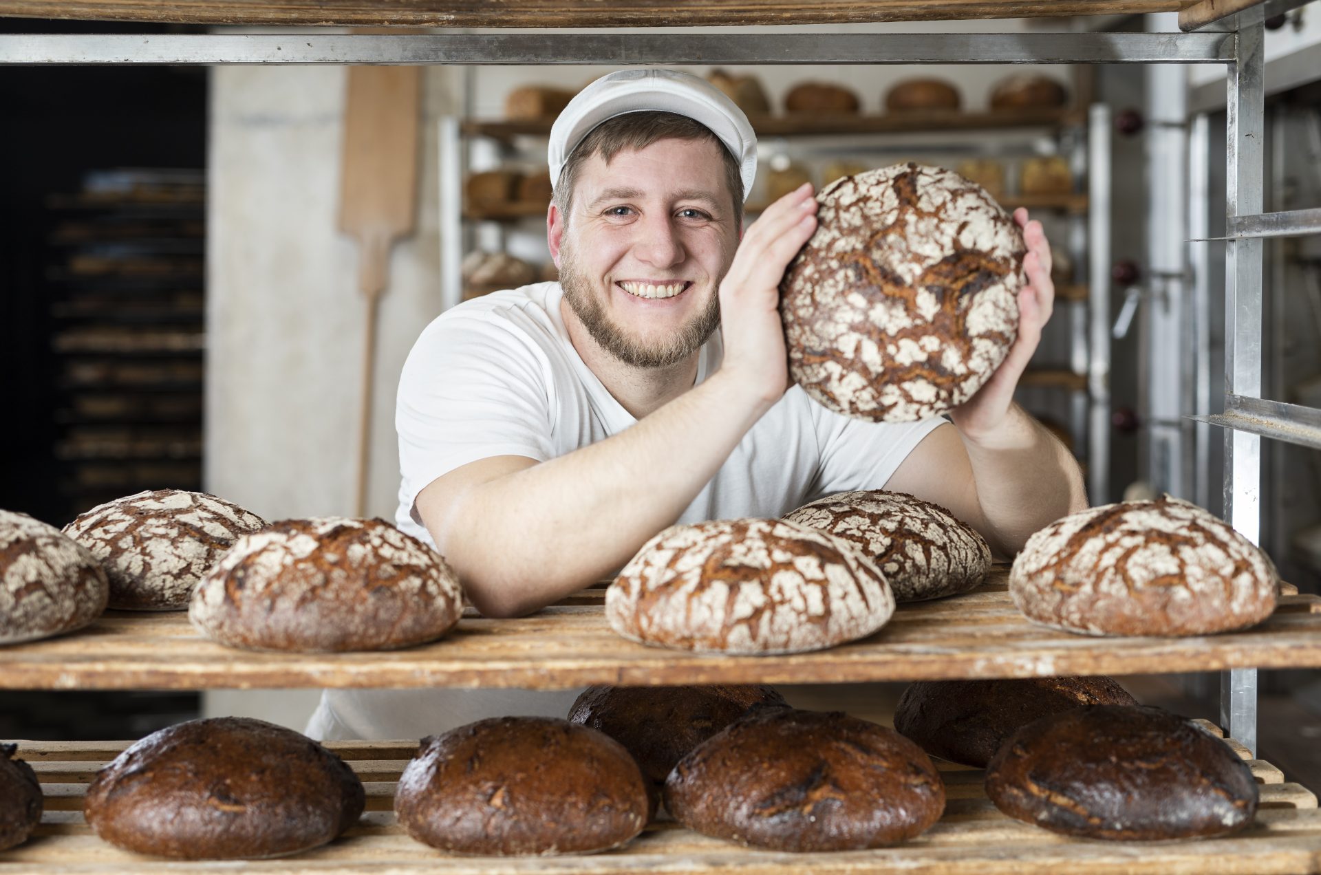 Bäcker Nick in seiner Backstube hält ein rundes, frisch gebackenes Brot.